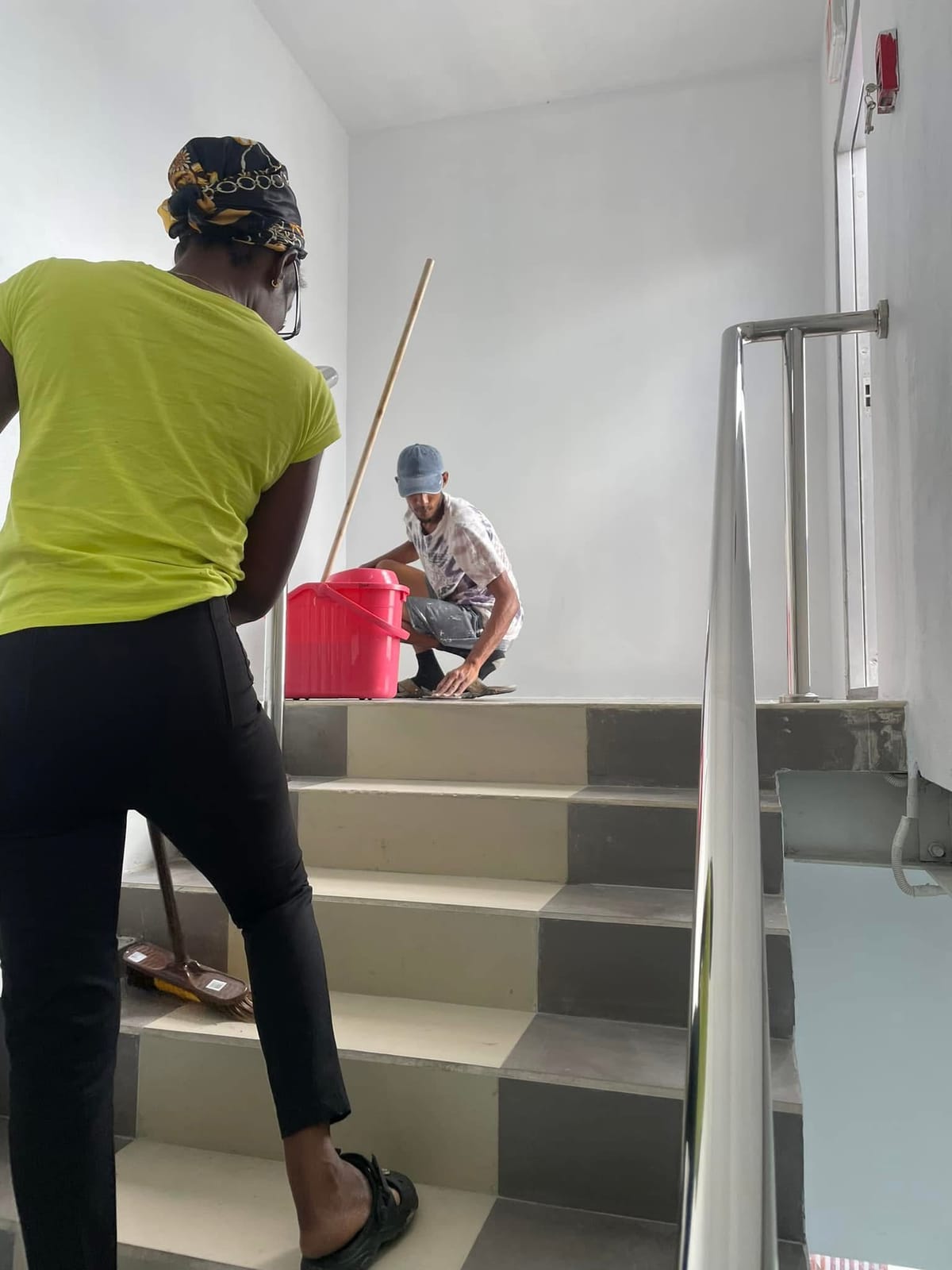 Two CDCS team members cleaning a commercial staircase and stainless steel handrail