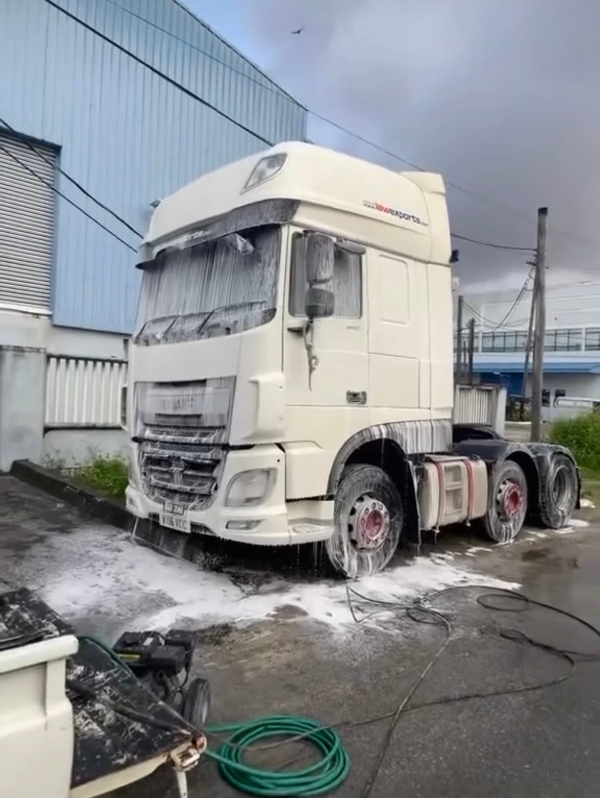 A commercial truck cab covered in cleaning foam during a CDCS fleet wash in Guyana